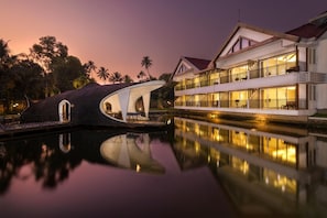 Un edificio de dos pisos con balcones y su reflejo en el agua.