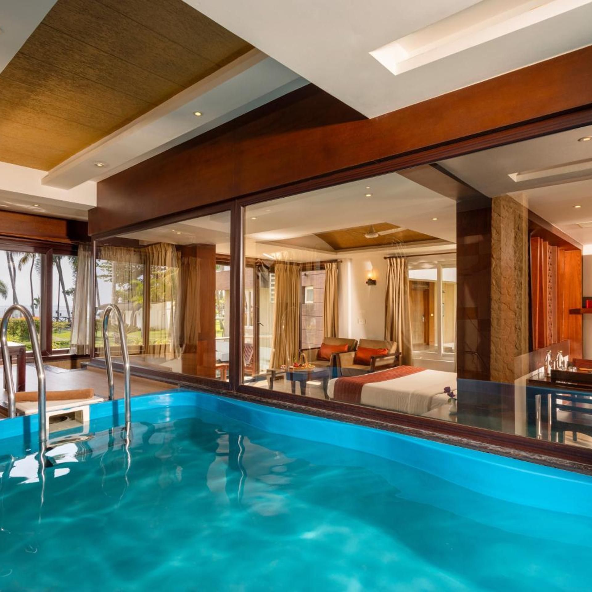 A hotel room with a large window, a pool, and a bed.