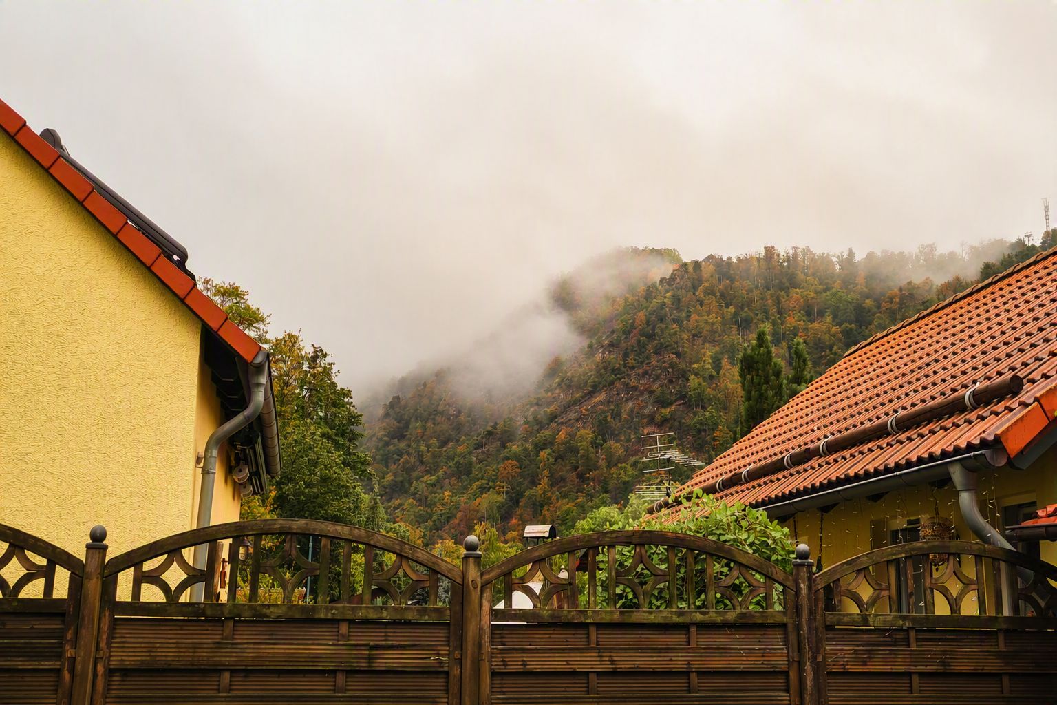 Ein Wohngebiet mit einem hölzernen Tor, gelben Wänden und einem roten Ziegeldach.