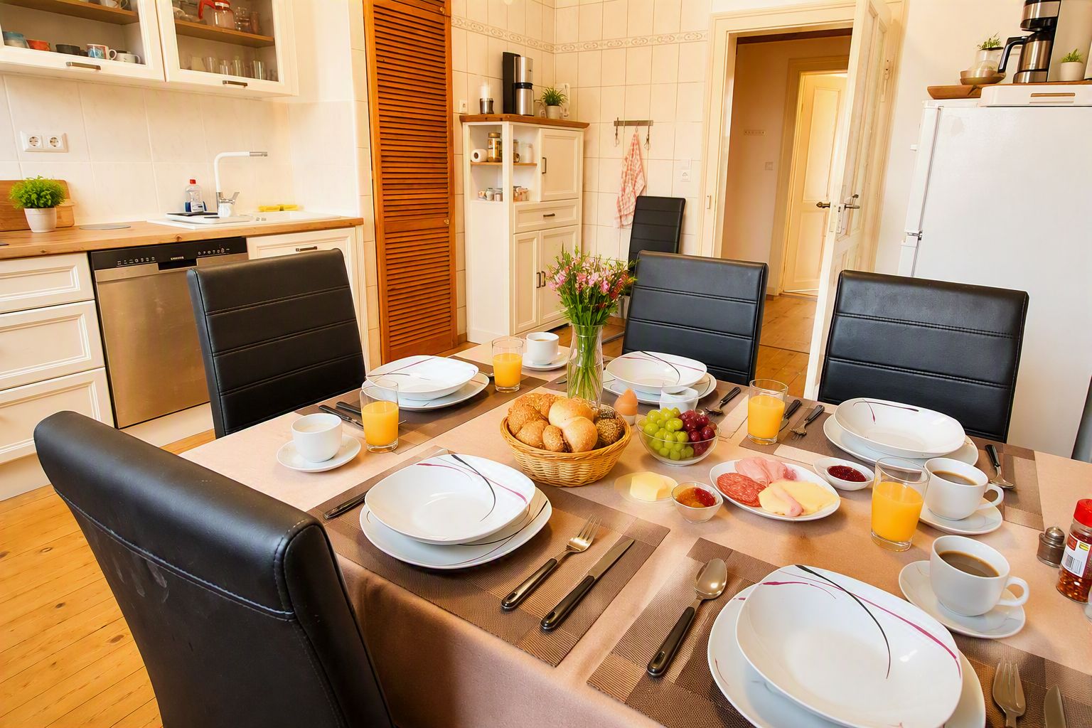 A breakfast setup with a table set for four, including plates, cutlery, and a variety of breakfast items.