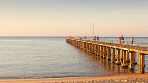 Eine Pier, die sich in ruhiges Wasser erstreckt, mit wolkenlosem Himmel.
