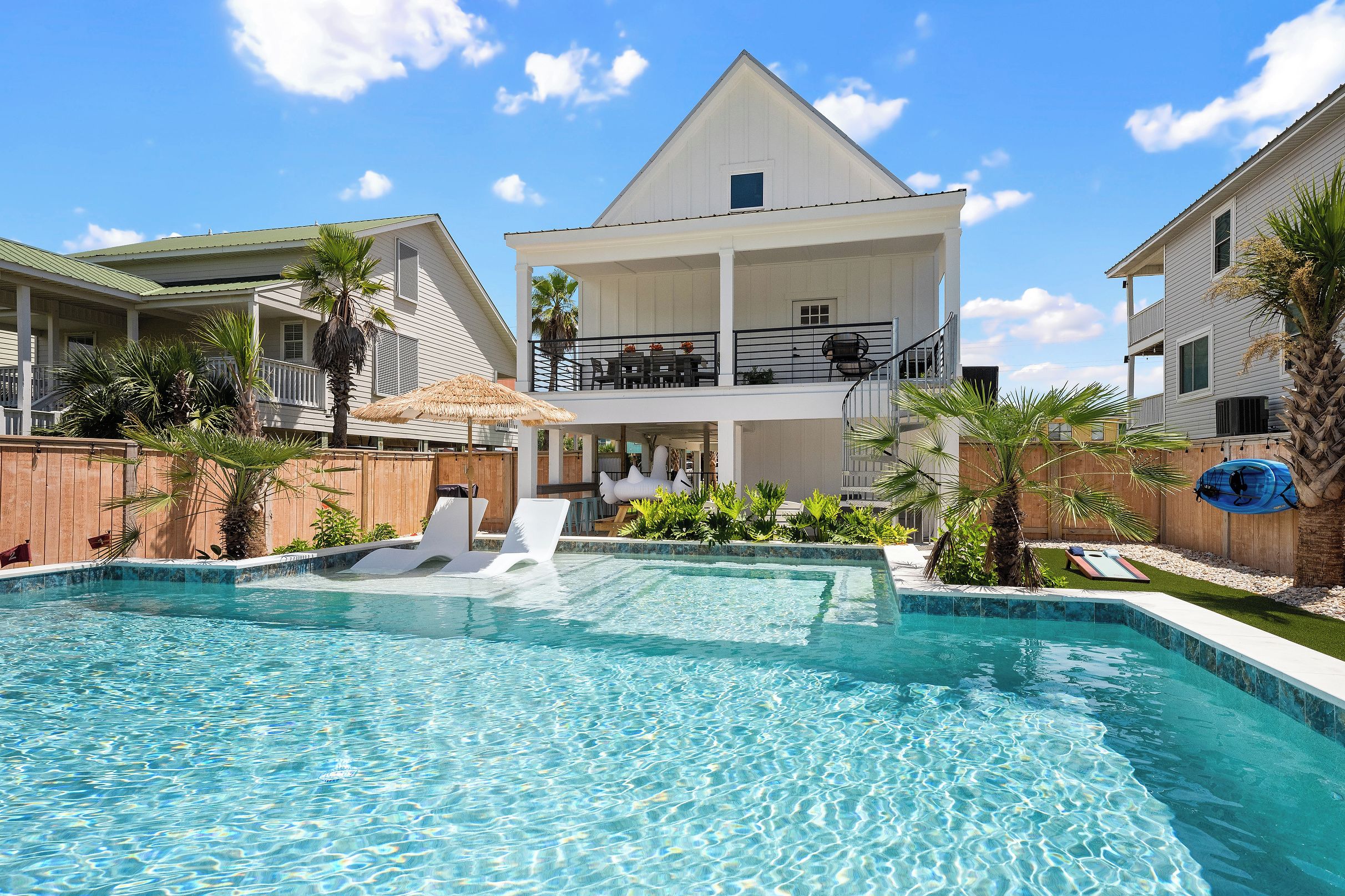 A swimming pool with a hot tub, lounge chairs, and a wooden deck.