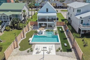 Ein Wohnhaus mit Swimmingpool, Sitzgelegenheiten im Freien und einem eingezäunten Garten.