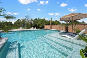 Ein klarer blauer Pool mit Liegestühlen und einer Palme.