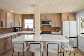 Una cocina moderna con armarios de madera, una isla central y taburetes de bar.