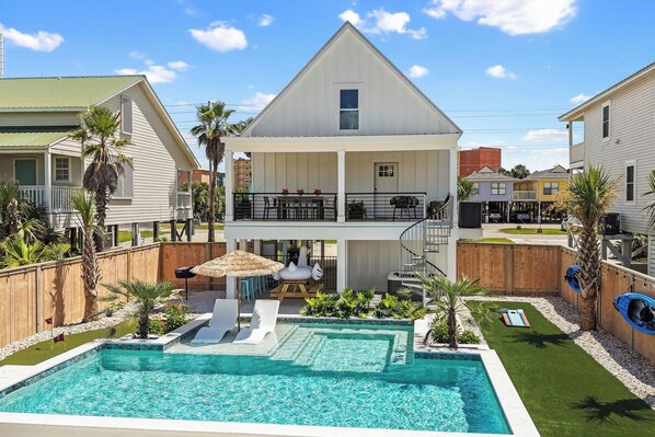 Ein zweistöckiges Haus mit Schwimmbad, überdachter Terrasse und umzäunter Garten.