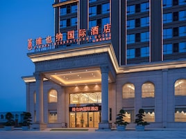 Un hotel con una entrada imponente, varios pisos y una fachada bien iluminada.