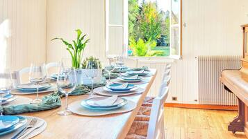 A dining table set for six with blue plates and clear glasses, surrounded by white chairs.