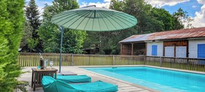 A swimming pool with a wooden deck, lounge chairs, and a covered umbrella. - Former bakery between forests and ocean at Lüe (LÜE)