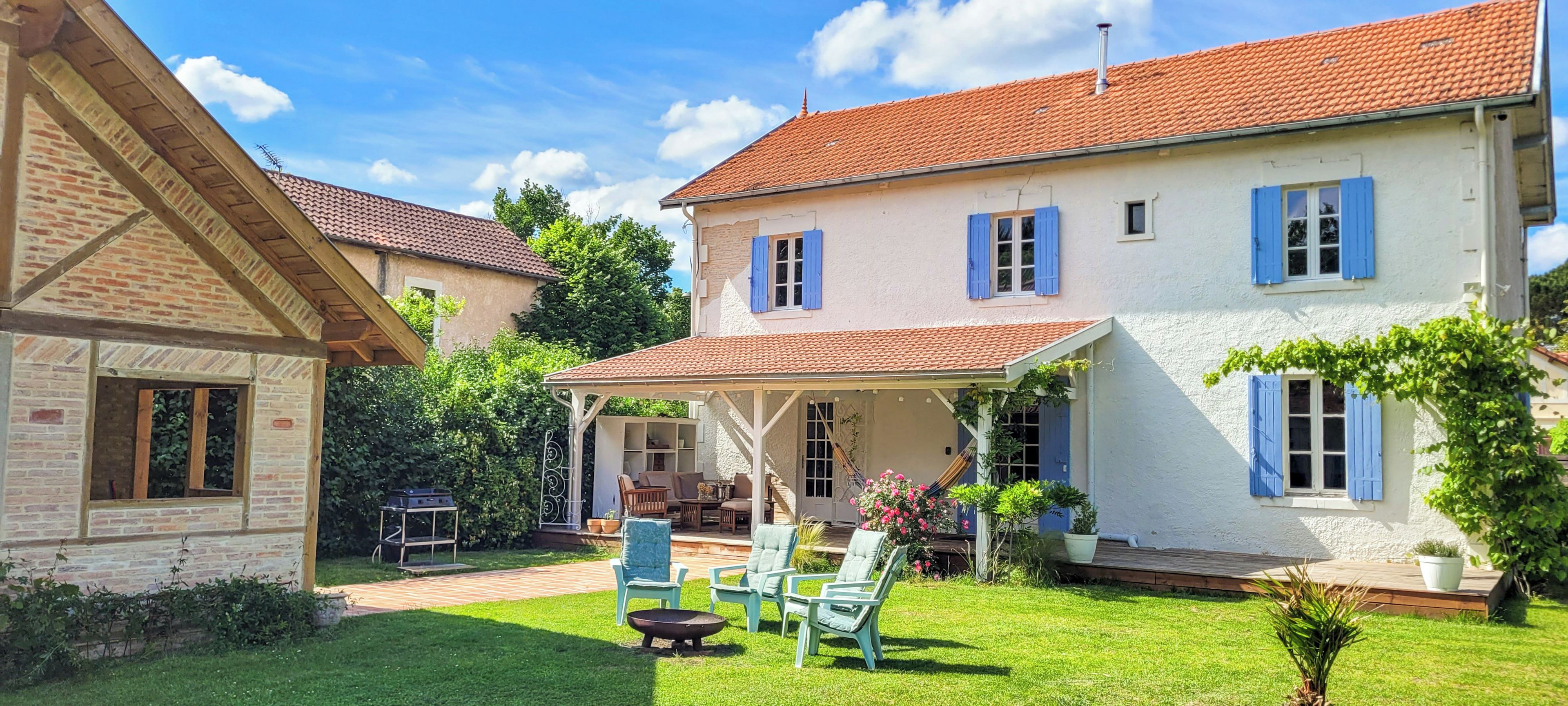 Une maison à deux étages dotée d’un patio couvert, d’une cheminée en briques et d’une pelouse bien entretenue.