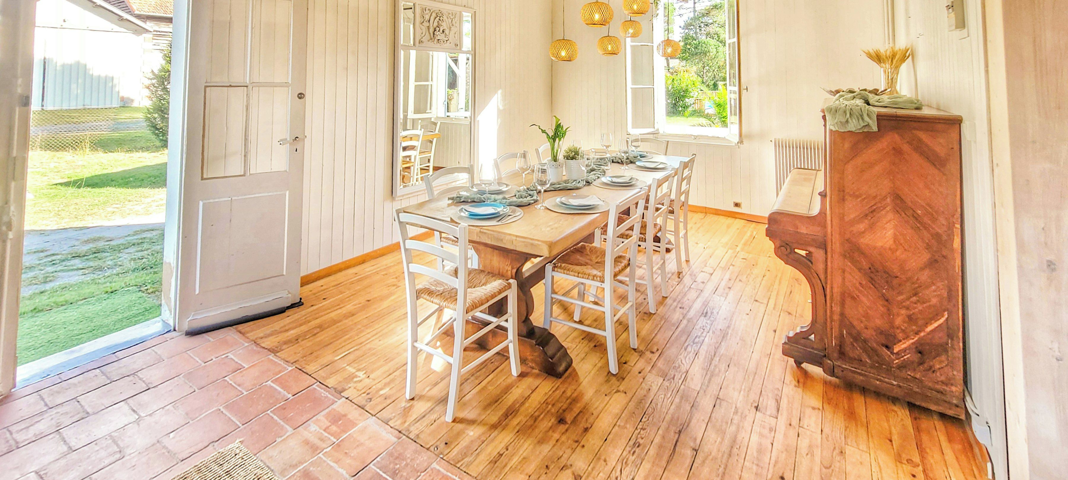 A dining area with a wooden table set for four, white chairs, and a wooden cabinet with a mirror.