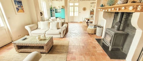 A cozy living room with a fireplace, a sofa set, and a wicker coffee table.