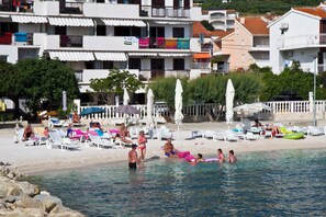Een hotel aan het strand met meerdere balkons, ligbedden en parasols.