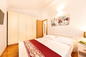 Een slaapkamer met een bed, een kledingkast, een schilderij en een nachtkastje.