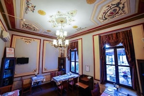 A dining area with a chandelier, tables, chairs, and a view through large windows. - Sarnic Suits & Kitchen (Istanbul)