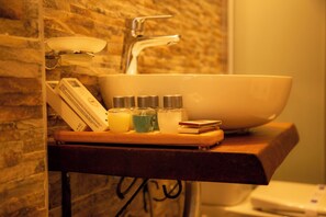 A bathroom sink with a large bowl, a mirror, and a wooden tray holding toiletries. - Sarnic Suits & Kitchen (Istanbul)