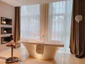 A modern bathroom with a freestanding bathtub, a round mirror, and a decorative floor lamp. - Crystal Orange Hotel (Tianjin)