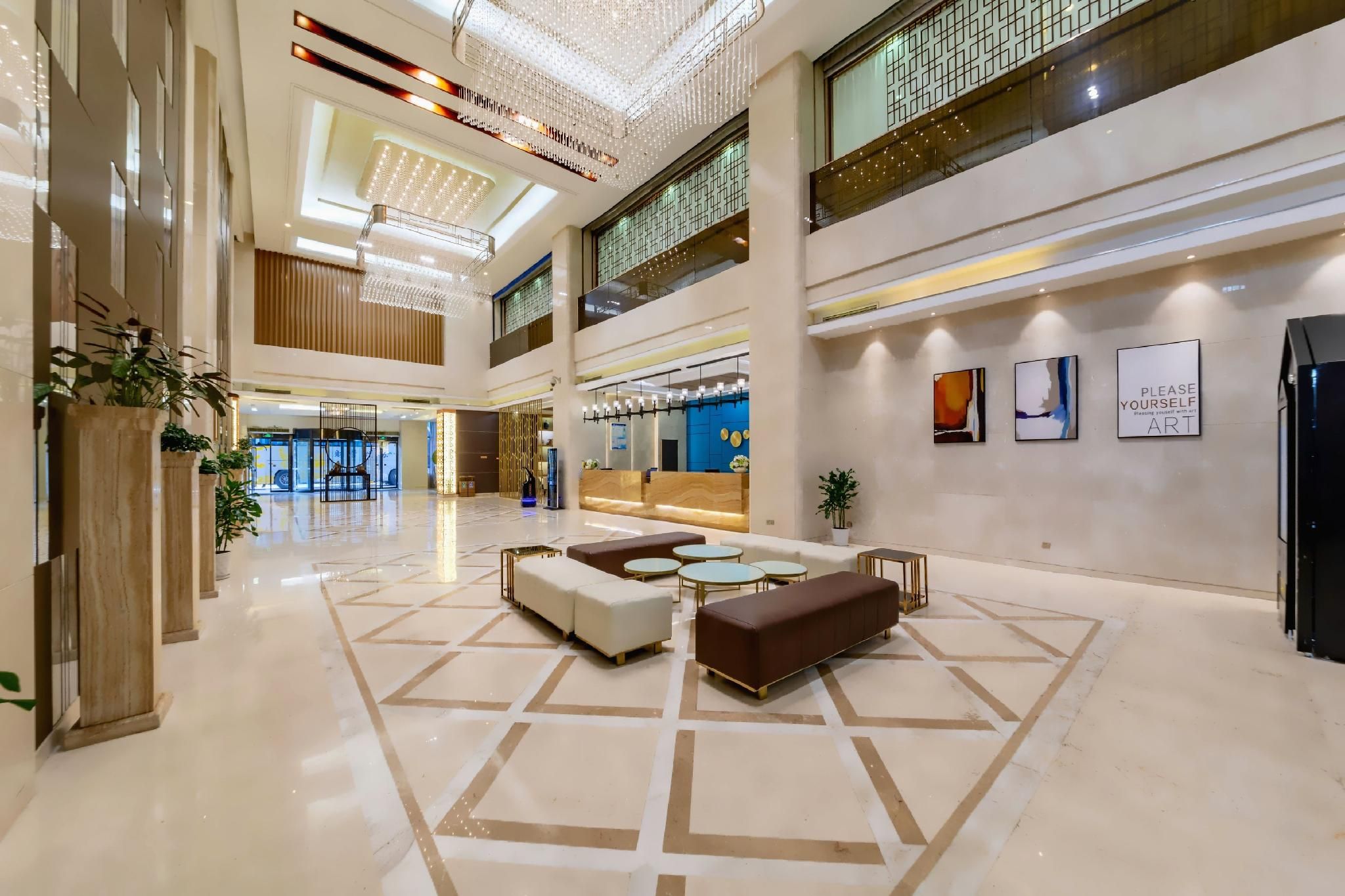 A spacious lobby with a reception desk, seating area, and a high ceiling with decorative lighting.