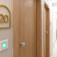 Una puerta de madera con un cartel numérico que indica el número 20, una manija y un interruptor de luz.