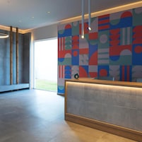 Un área de recepción con diseño moderno, que presenta una gran obra de arte abstracta y un mostrador de recepción.