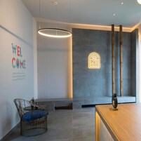 Una moderna área de recepción con un cartel que dice 'WELCOME', una lámpara de pared única y un mostrador de recepción de madera.