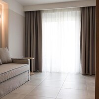 Una sala de estar moderna con un sofá, una mesita y un ventanal con cortinas.
