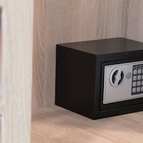 A black safe with a numeric keypad on a wooden surface.