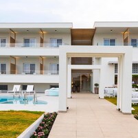 A modern hotel with a pool, outdoor seating, and a covered entrance.