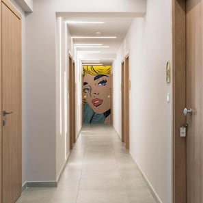 A hotel corridor with wooden doors, a tiled floor, and a pop art mural on the wall. - Motivo Thassos (Thasos)