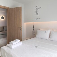 A hotel room with a bed, a wall-mounted light fixture, and a motivational quote on the wall.