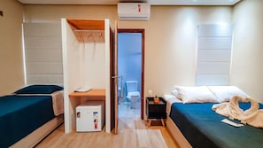 Una habitación con dos camas, un escritorio, un archivador pequeño y una puerta que da al baño.