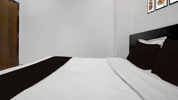 Un dormitorio con cama, una puerta de madera y cuadros en la pared.