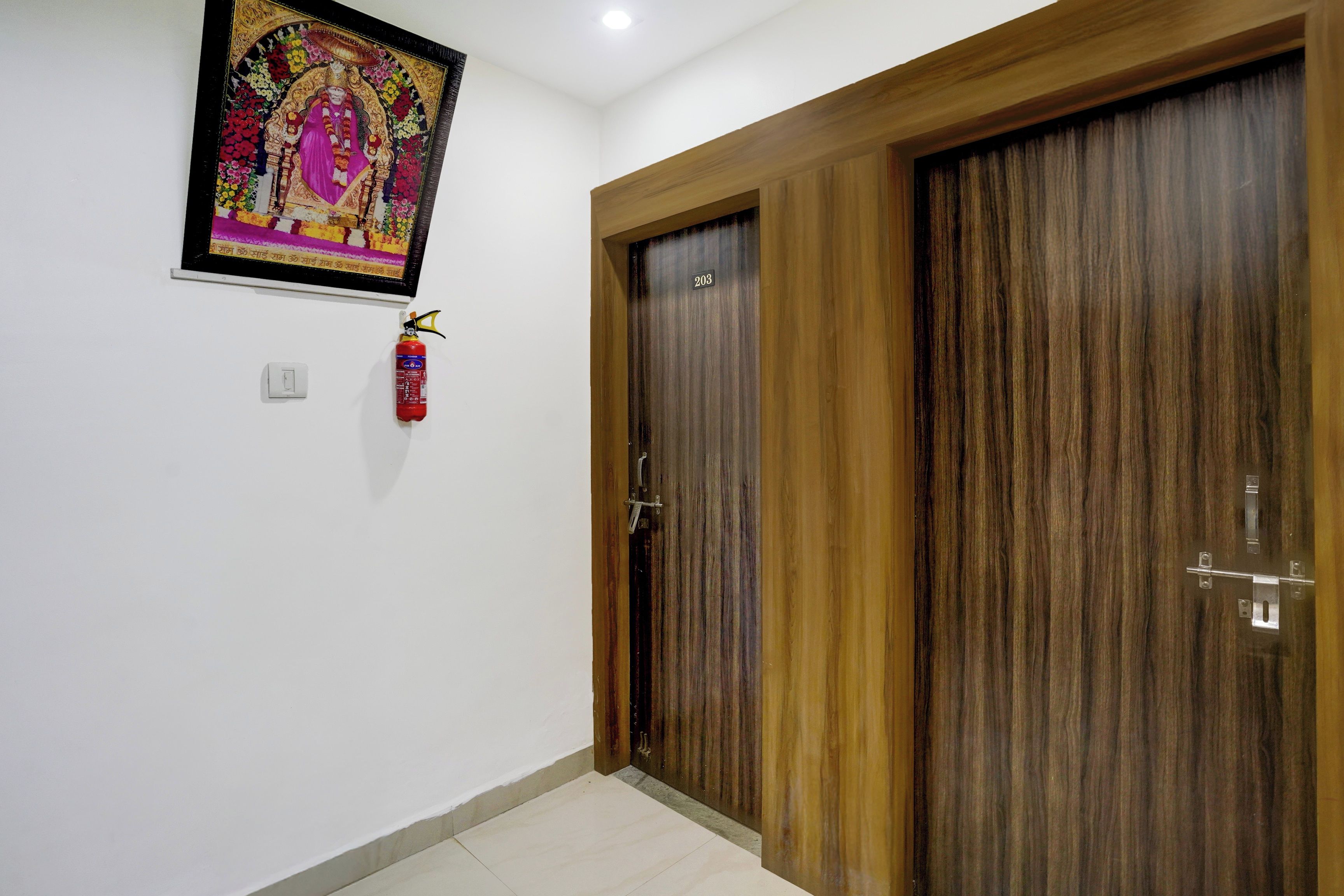 Una habitación con puerta de madera, un extintor y un cuadro en la pared.