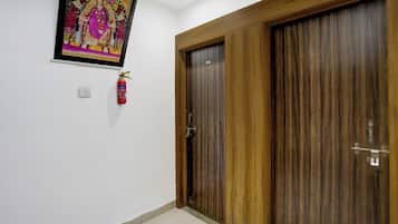 Una habitación con puerta de madera, un extintor y un cuadro en la pared.