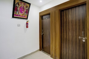 Une pièce avec une porte en bois, un extincteur et un tableau encadré accroché au mur.