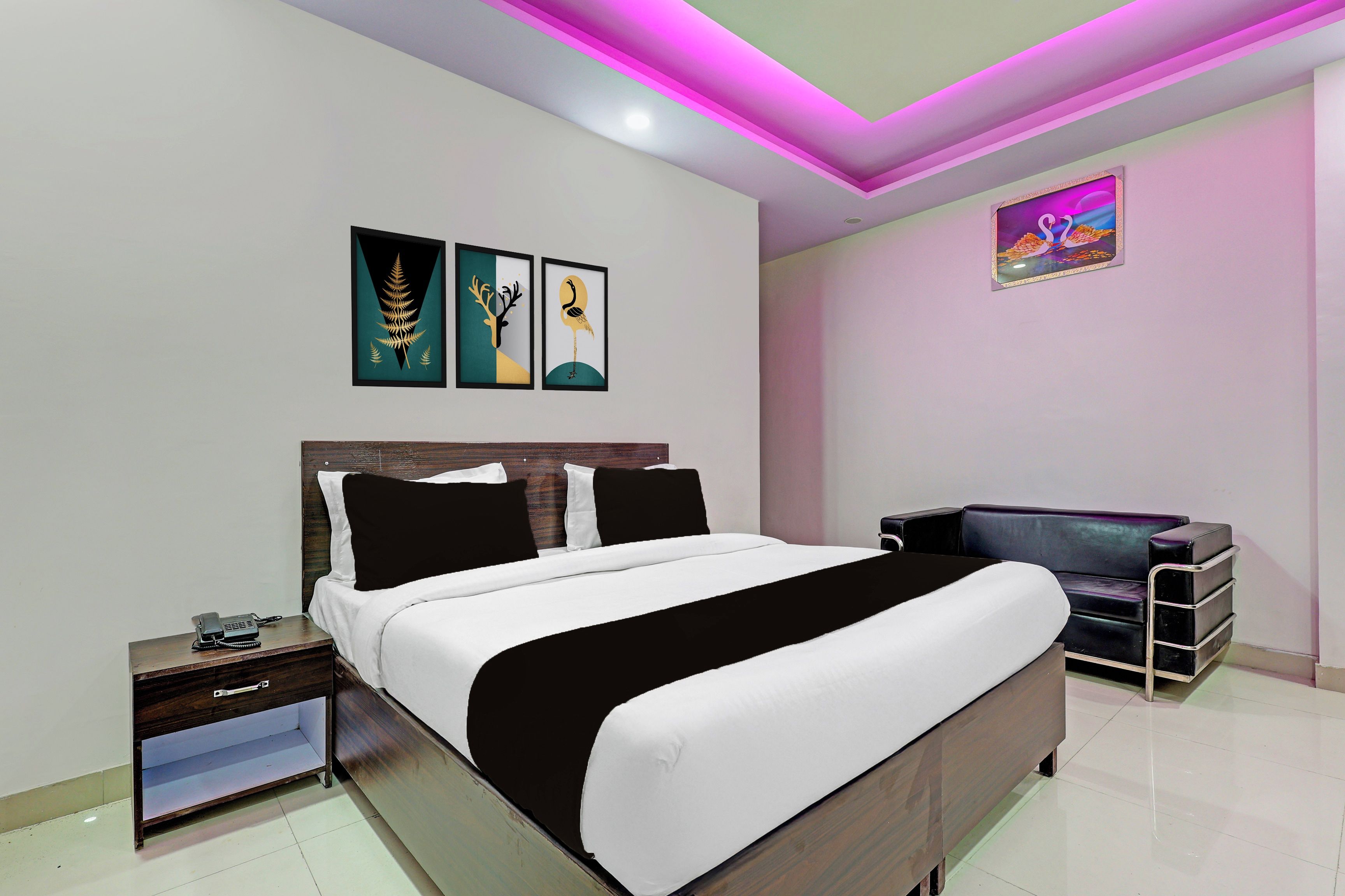 Quarto moderno com cama, mesas de cabeceira, um sofá e obras de arte nas paredes.