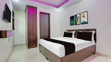 Une chambre à coucher moderne avec un grand lit, un téléviseur à écran plat fixé au mur et des œuvres d’art au-dessus du lit.