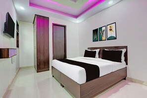 Un dormitorio moderno con una cama grande, un televisor de pantalla plana en la pared y una obra de arte sobre la cama.