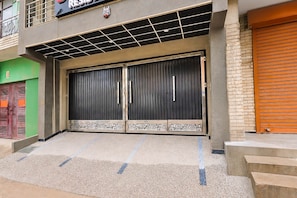 A building with a large, dark-colored double door with decorative patterns at the bottom. - Collection O Palam Metro Station (New Delhi)