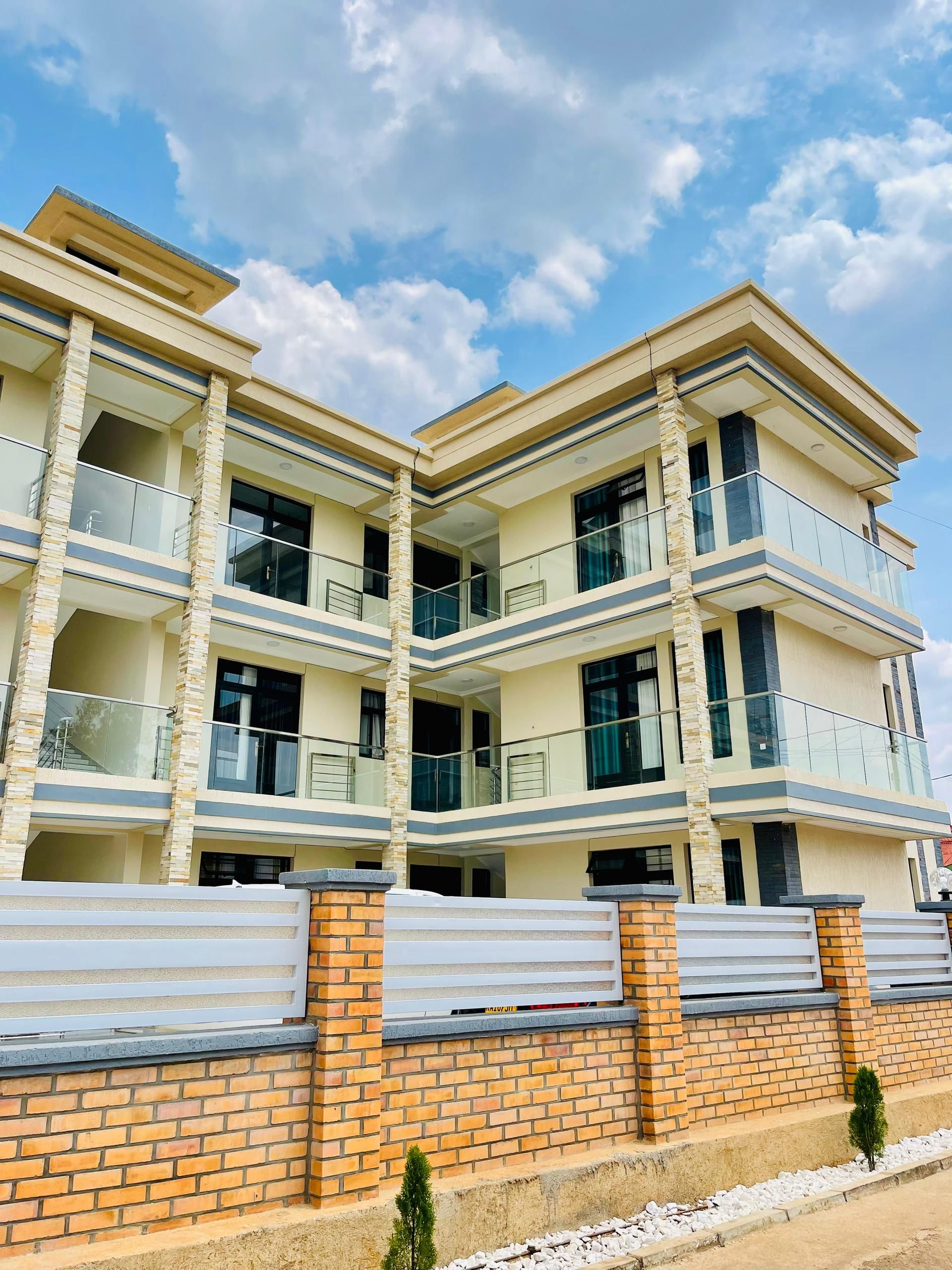 A multi-story residential building with balconies, brick walls, and a clear sky.