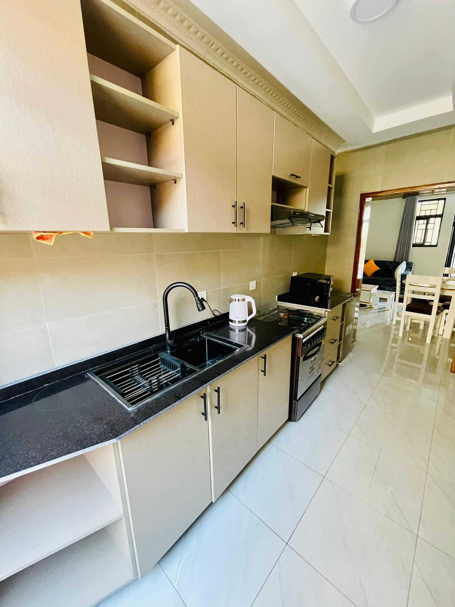 A modern kitchen with a black countertop, stainless steel appliances, and beige cabinetry.