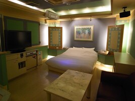 Una habitación de hotel con una cama, televisión, escritorio y silla.
