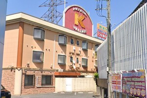 Um hotel com uma placa grande em vermelho e amarelo, várias janelas e entrada fechada por grades.