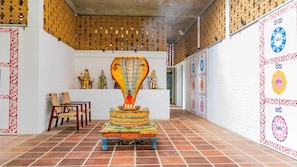 Een tempelinterieur met een centraal altaar, beelden en een betegelde vloer.
