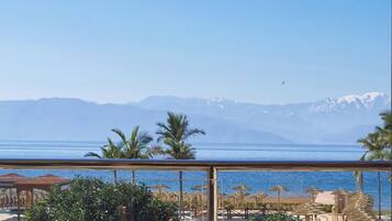 A balcony with a view of a beach and mountains.