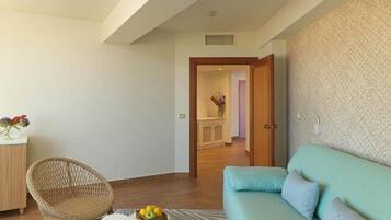 Un salón con un sofá, una silla de mimbre, una mesita con fruta y una pared con diseño decorativo.