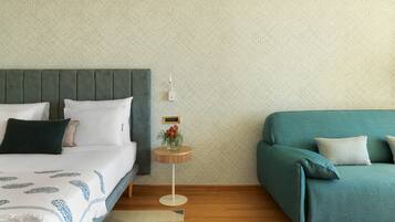 A bedroom with a bed, bedside table, and a green sofa.