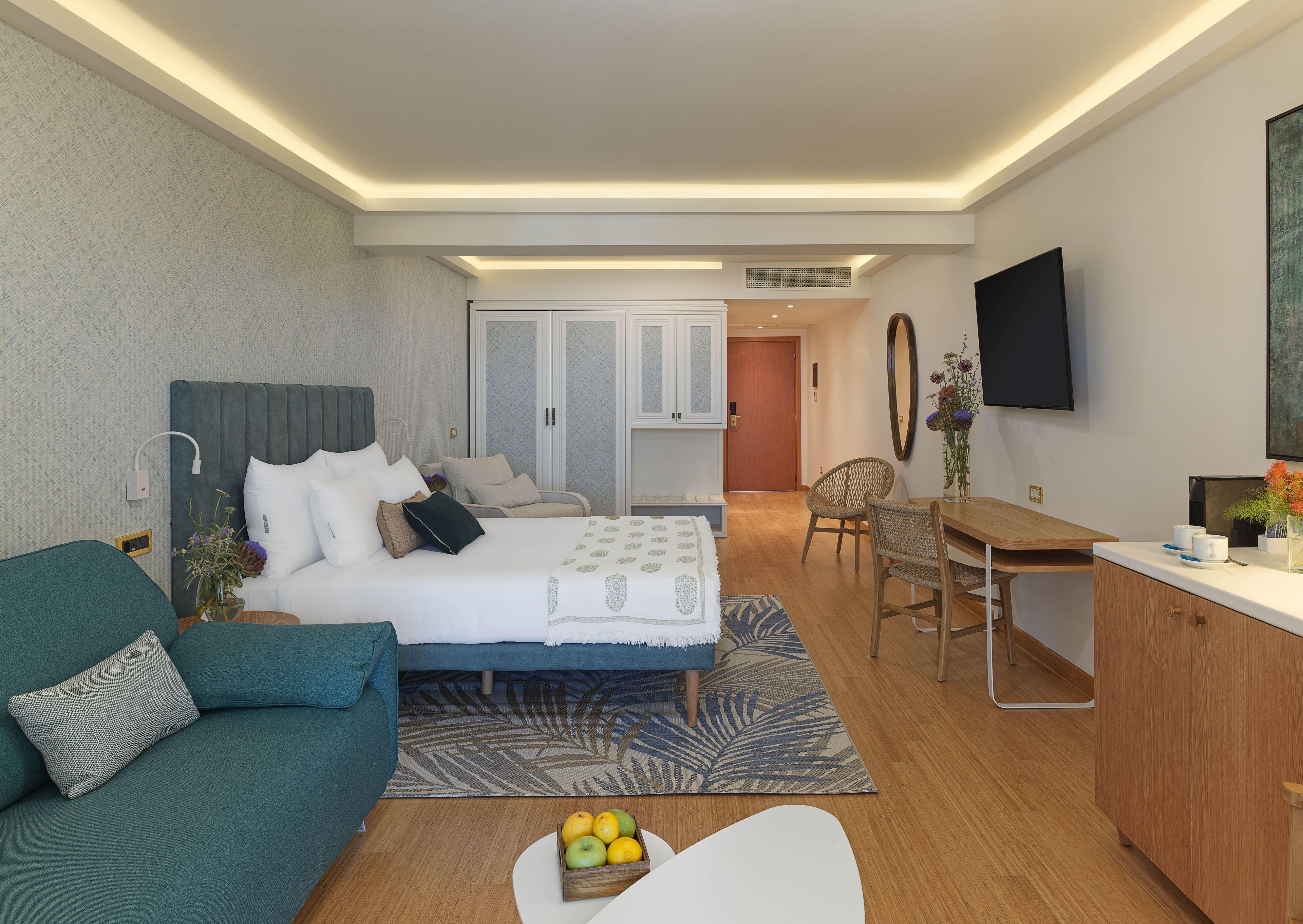 Una habitación de hotel moderna con cama, sofá, escritorio y televisor.