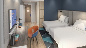 Une chambre d’hôtel avec deux lits, un bureau, une chaise, une télévision et une porte de salle de bain.