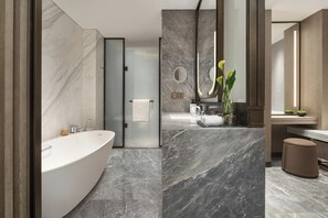 Un baño moderno con una bañera independiente, ducha con mampara de vidrio y tocador con espejo.